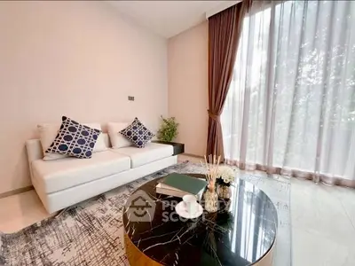 Elegant living room with modern sofa, stylish coffee table, and large window with sheer curtains.