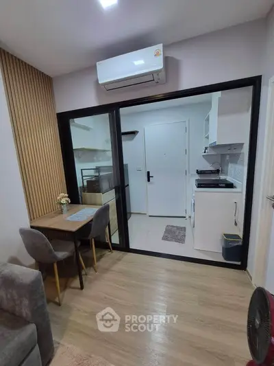 Modern apartment interior with open kitchen and dining area, featuring sleek design and air conditioning.