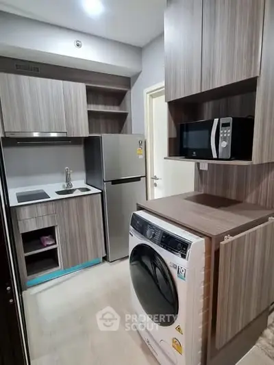 Modern compact kitchen with washing machine and microwave in stylish apartment