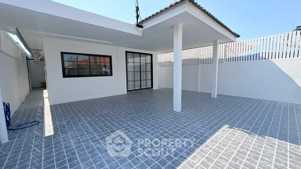 Spacious modern outdoor patio with tiled flooring and covered area, perfect for entertaining.
