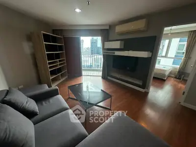 Spacious living room with modern furniture and city view balcony in a high-rise apartment.