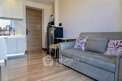 Modern living room with cozy gray sofa and compact kitchen in open layout apartment.