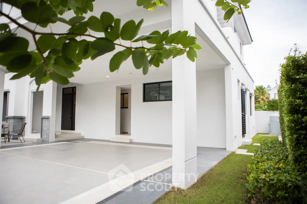 Modern white exterior with spacious covered patio and lush greenery