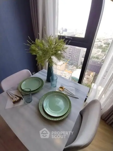 Chic dining setup with city view from high-rise apartment window.