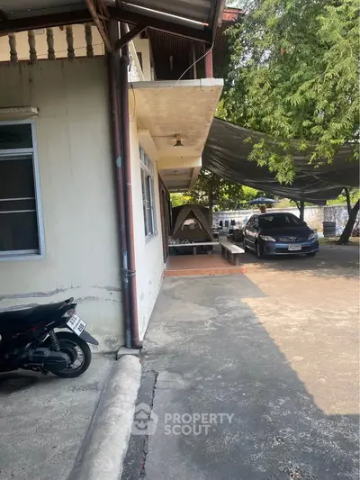 Charming residential exterior with shaded parking and lush greenery, perfect for outdoor relaxation.