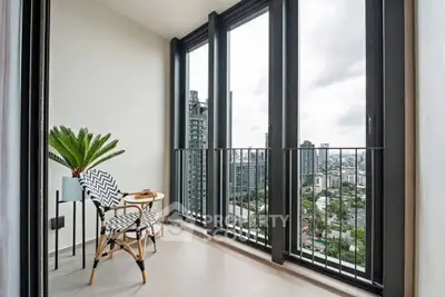 Stunning city view from modern balcony with stylish seating and floor-to-ceiling windows.