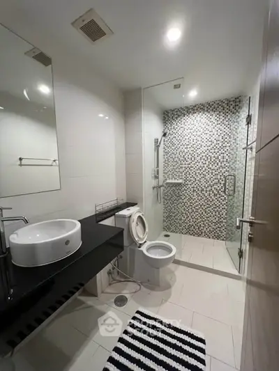 Modern bathroom with sleek design, featuring a glass shower enclosure and stylish fixtures.