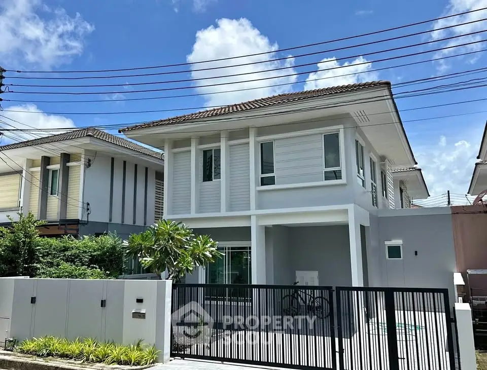 Modern two-story house with a sleek design and spacious driveway under a clear blue sky.