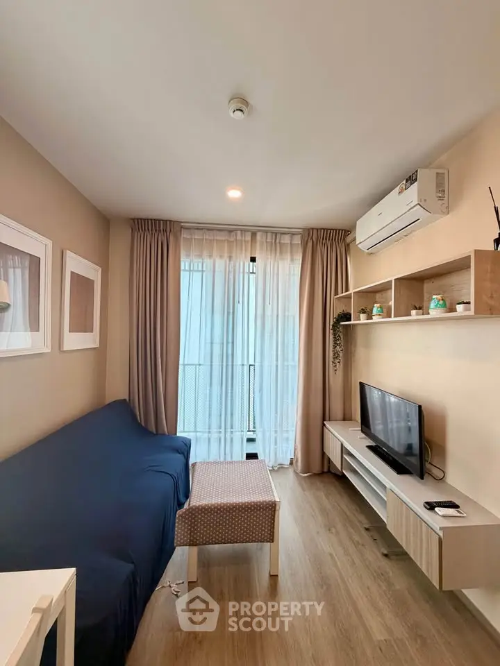 Cozy living room with modern decor, featuring a comfortable sofa, TV, and air conditioning.
