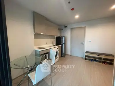 Modern compact kitchen with washing machine and dining area in a cozy apartment.