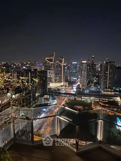 Stunning city skyline view from a high-rise balcony at night, showcasing vibrant urban lights.