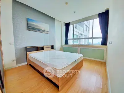 Spacious bedroom with large window offering stunning views in modern apartment.