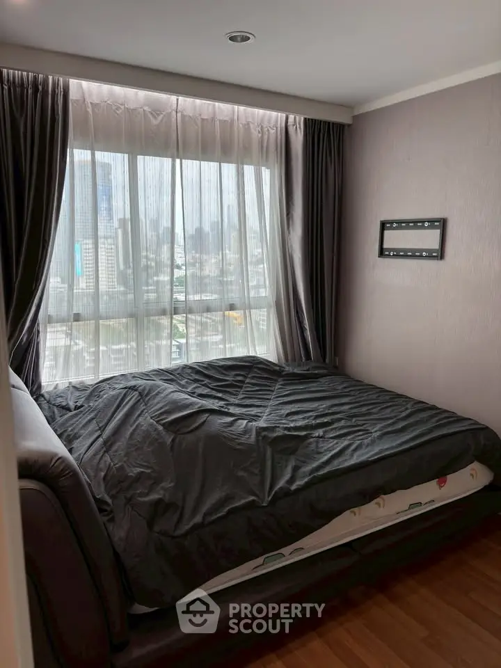 Cozy bedroom with city view, featuring a large window and modern decor, perfect for urban living.