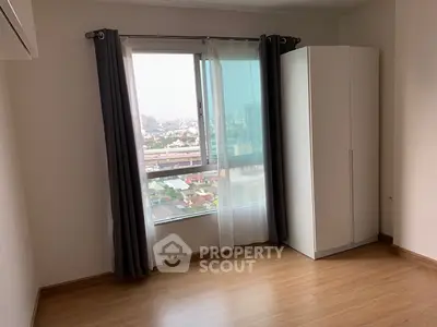 Spacious bedroom with large window offering stunning city view and ample natural light.
