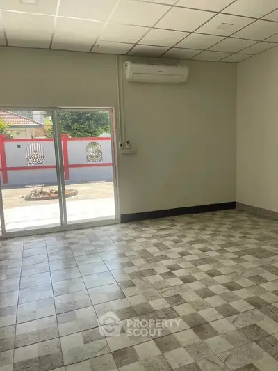 Spacious tiled room with air conditioning and sliding glass doors leading to outdoor area.