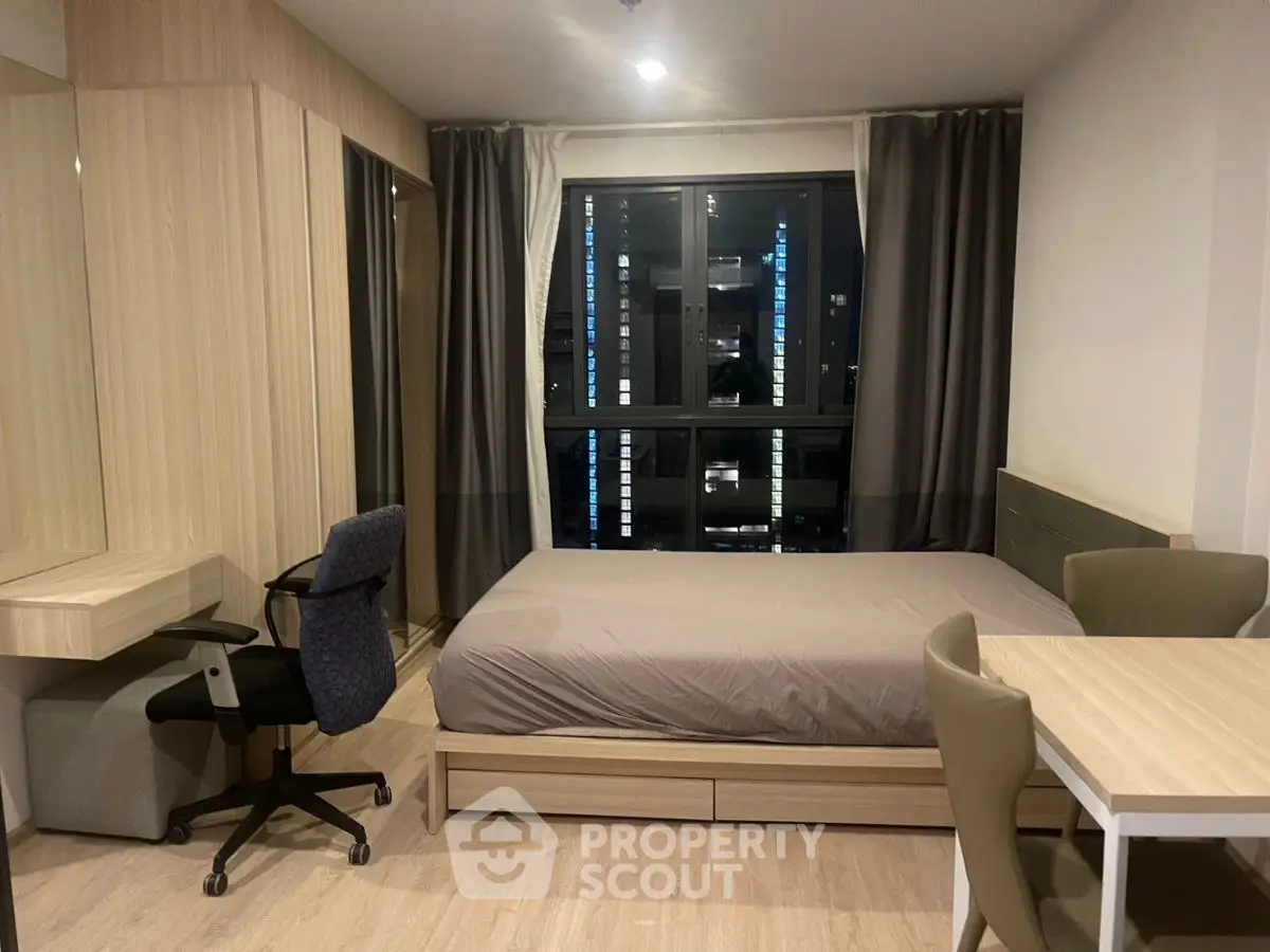 Modern bedroom with sleek furniture and large window in urban apartment