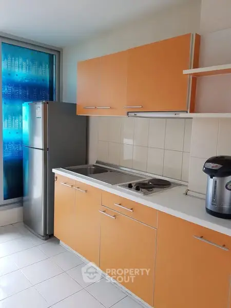 Modern kitchen with orange cabinets and stainless steel appliances