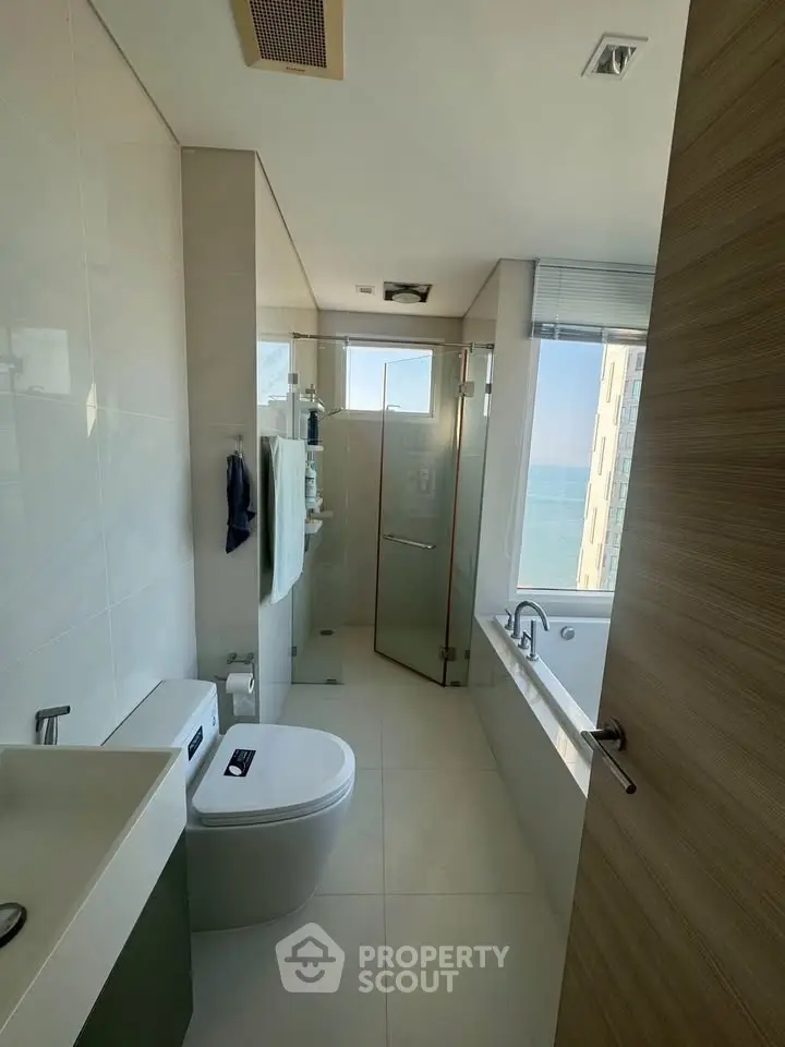 Modern bathroom with sleek design, featuring a glass shower and a bathtub with a view.