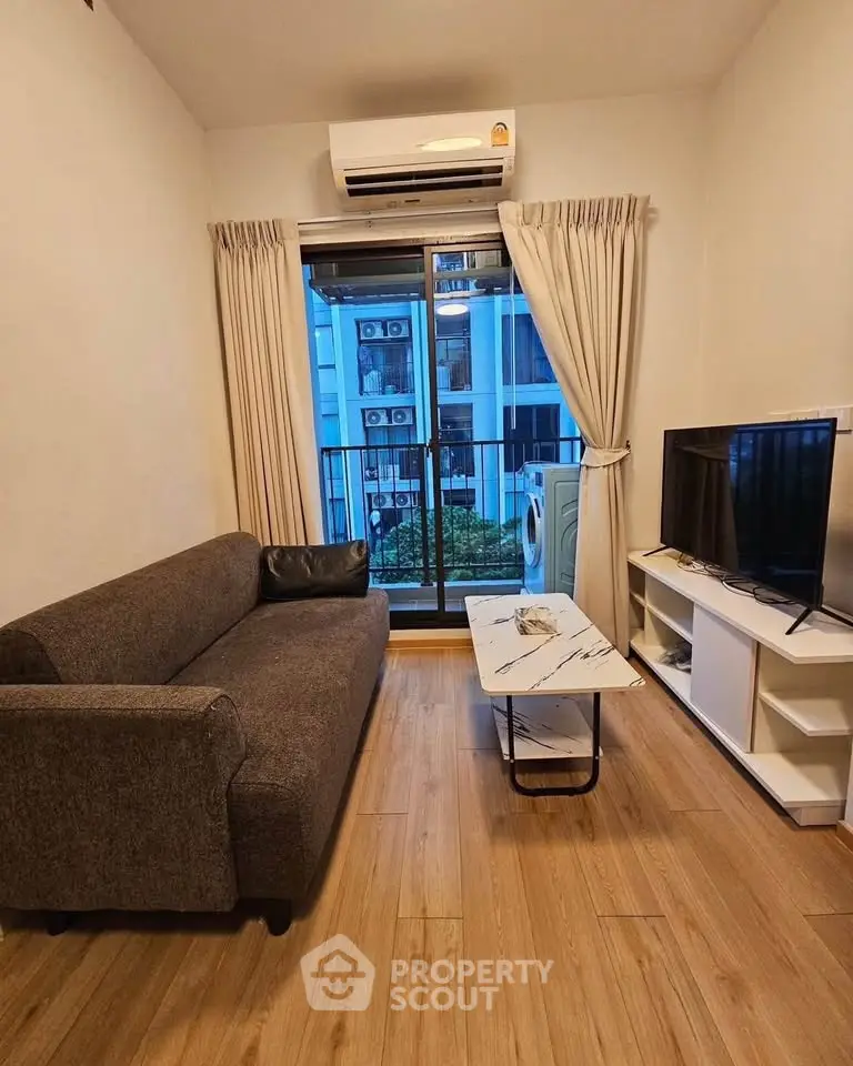 Cozy living room with modern sofa, TV, and balcony view in stylish apartment.