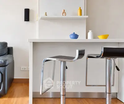 Modern kitchen with sleek bar stools and stylish decor in a contemporary apartment.