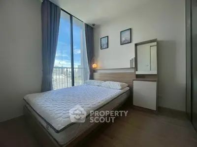 Modern bedroom with large window and stylish decor in a high-rise apartment.