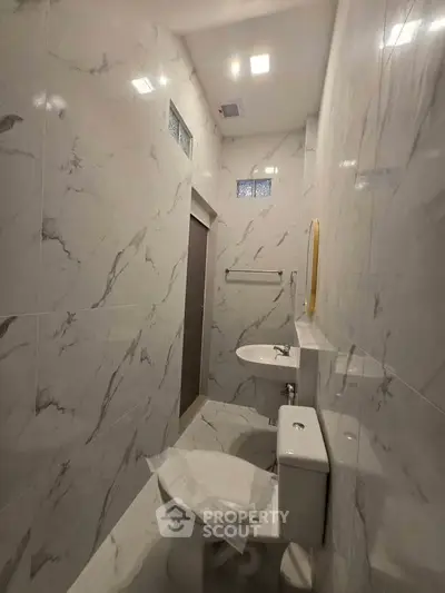 Luxurious marble-tiled bathroom with modern fixtures and elegant lighting.
