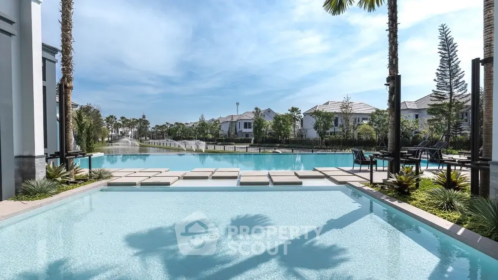 Luxurious poolside view with palm trees and elegant architecture in a serene residential setting.