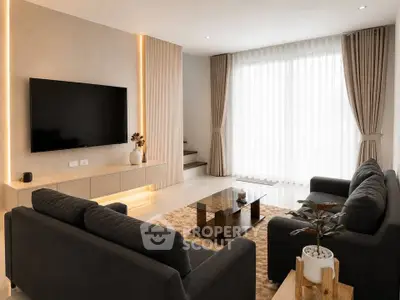 Modern living room with sleek furniture and large TV, featuring elegant curtains and ambient lighting.