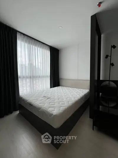 Modern bedroom with large window and minimalist decor in a high-rise apartment.
