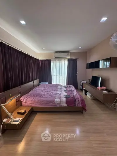 Spacious bedroom with modern decor and large window for natural light.