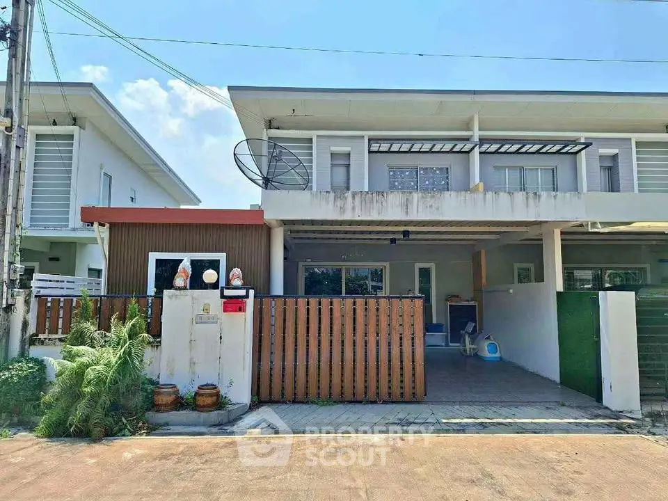 Modern two-story townhouse with gated entrance and satellite dish, featuring a small front garden.