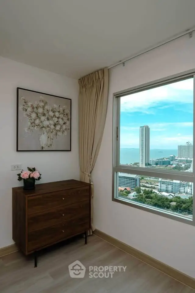 Stylish room with elegant decor and stunning city view from the window, featuring a chic dresser and floral artwork.