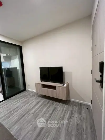 Modern living room with sleek flooring and mounted TV unit, adjacent to a balcony.