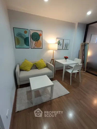 Cozy living room with modern decor, wooden flooring, and stylish furniture in a compact apartment.