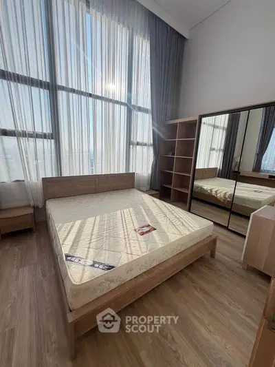 Spacious bedroom with floor-to-ceiling windows and modern wooden furniture.