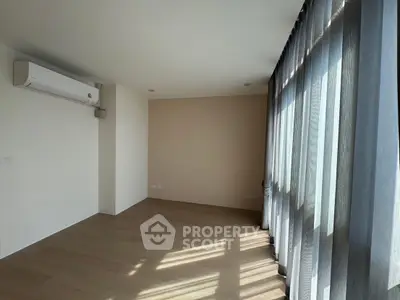 Spacious sunlit room with wooden flooring and large windows, perfect for modern living.