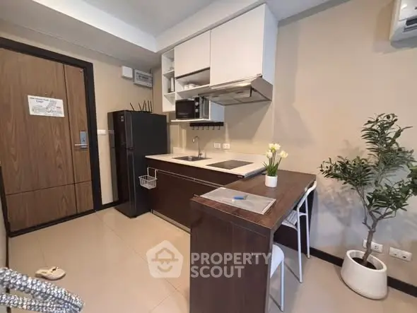 Modern kitchen with sleek cabinetry and compact dining area in stylish apartment.