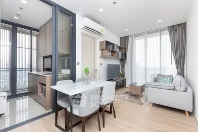 Modern open-plan living room with dining area and kitchen in a bright apartment.