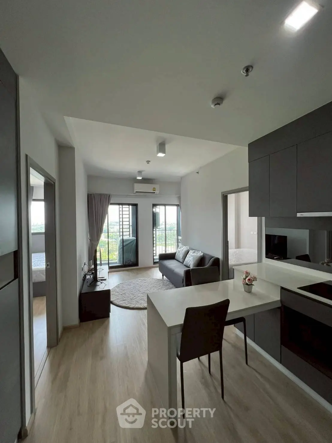 Modern open-plan living room with kitchen and balcony view in a stylish apartment.