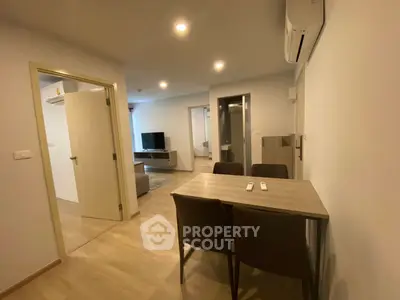 Modern apartment interior with dining area and living room, featuring sleek furniture and ambient lighting.