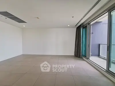 Spacious empty living room with large windows and balcony access