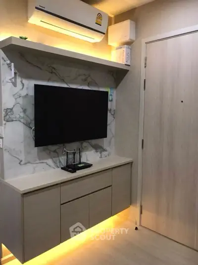 Modern living room with wall-mounted TV and stylish cabinetry under ambient lighting.