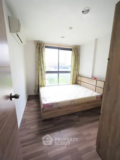 Cozy bedroom with wooden flooring and large window for natural light