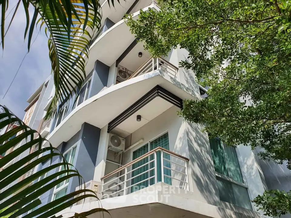 Modern apartment building exterior with balconies and lush greenery
