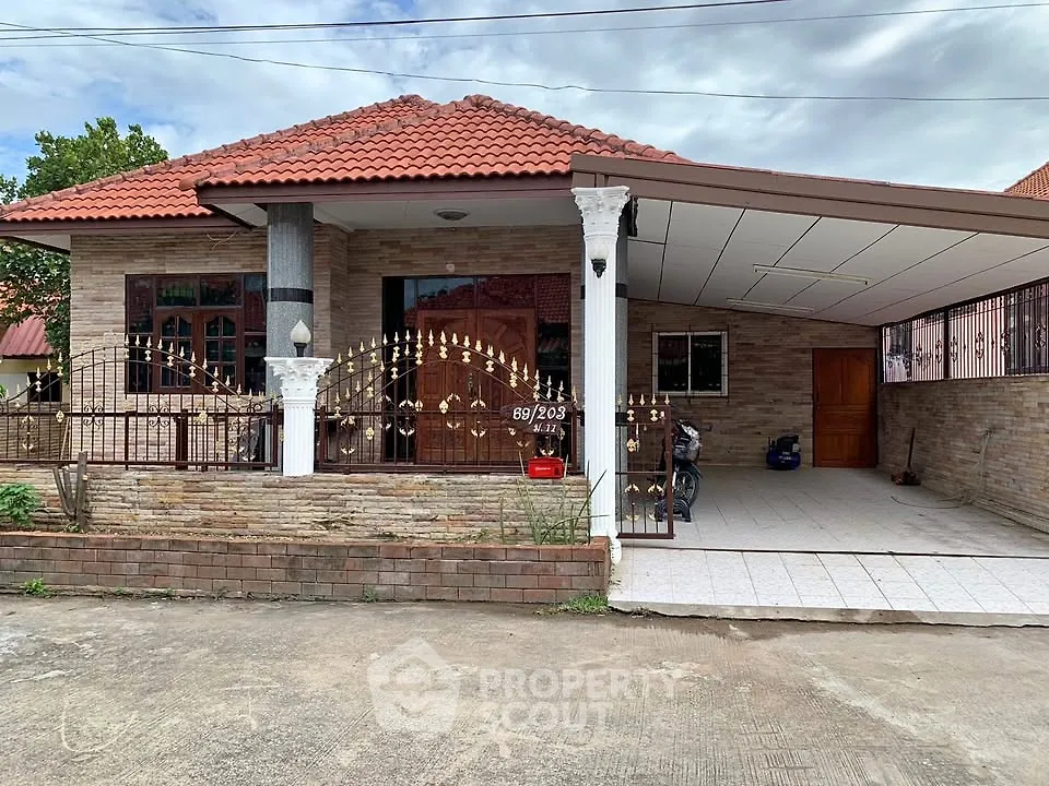 Charming single-story house with red-tiled roof and spacious carport in a serene neighborhood.