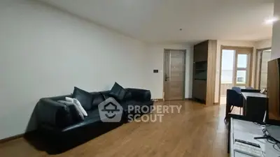 Spacious modern living room with sleek black sofa and wooden flooring