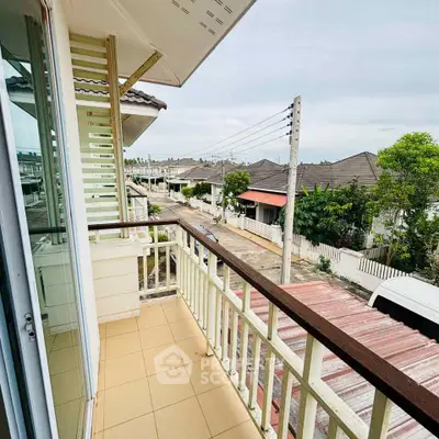 Charming balcony view overlooking a serene residential neighborhood with tiled roofs and lush greenery.