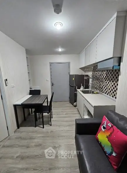 Modern kitchen with dining area in a cozy apartment, featuring sleek cabinetry and stylish backsplash.