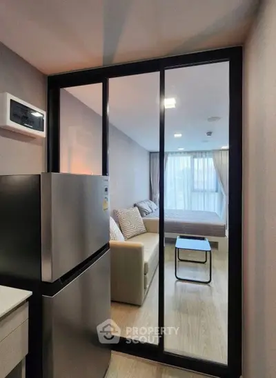 Modern apartment with sleek kitchen and cozy living area, featuring a large window for natural light.