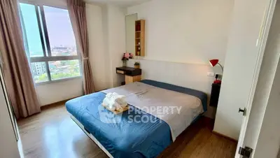 Cozy bedroom with large window and city view, featuring modern decor and wooden flooring.